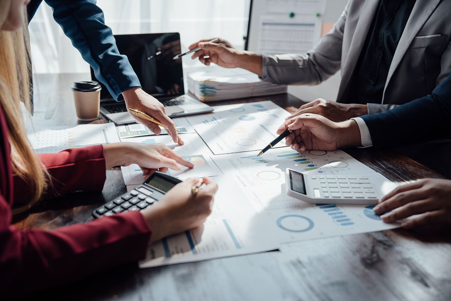A group of lawyers sits at a table and talks about statistics and other documents that are arranged in order on the table