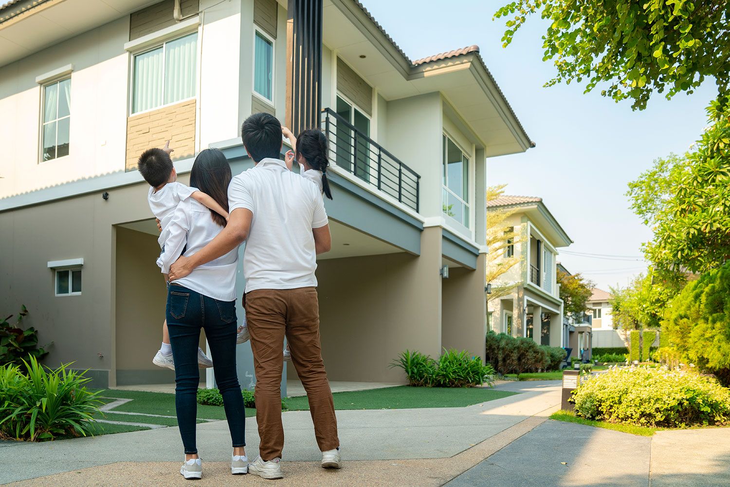 Family of four looks at a large, modern house from the outside
